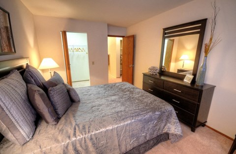 a bedroom with a large bed and a dresser and a bathroom