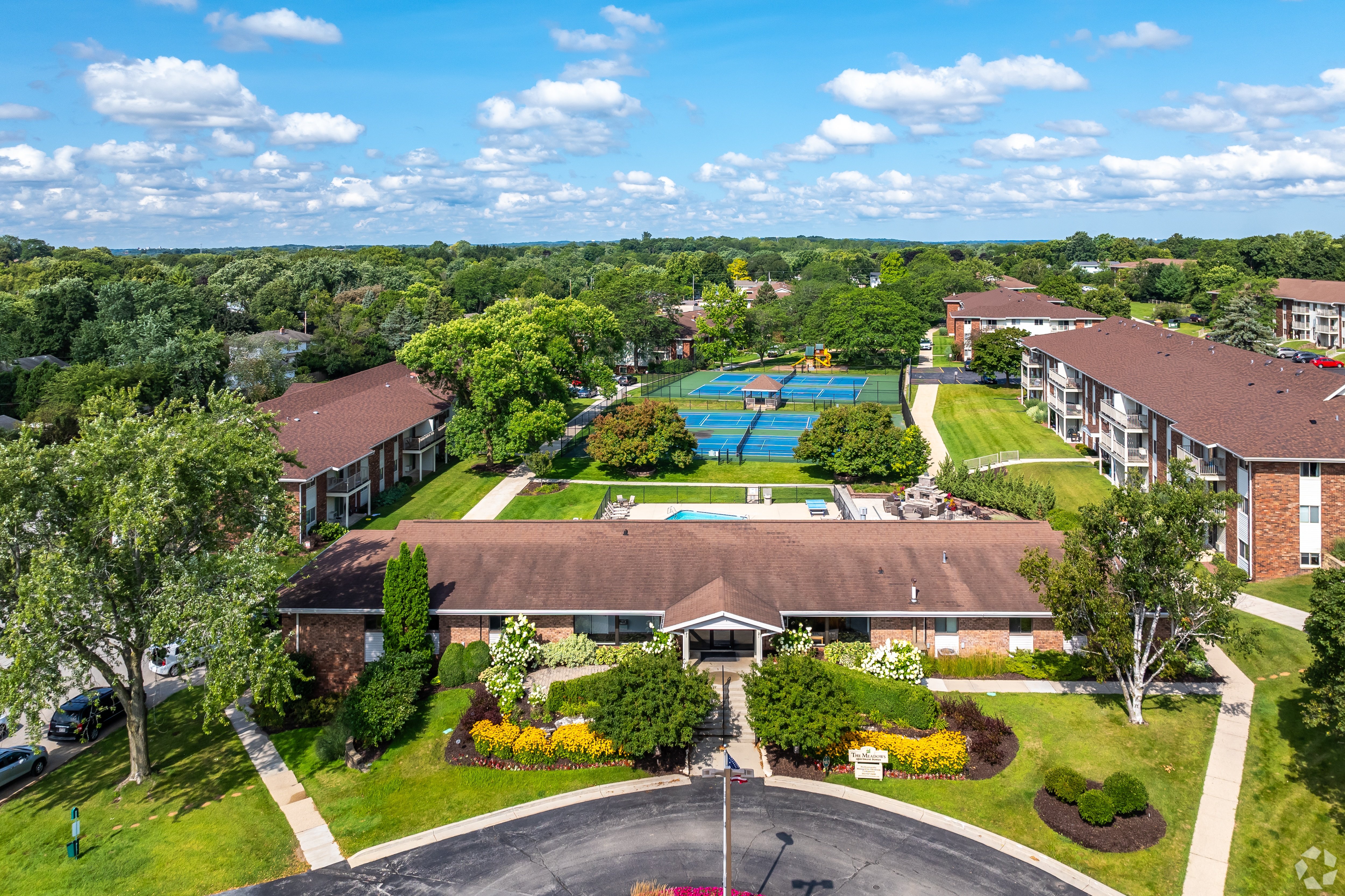 A large building with a pool in the middle of a green lawn.