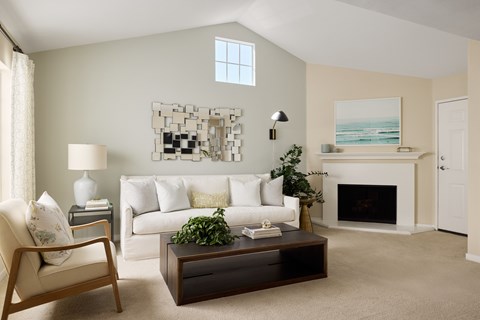 A living room with a white couch, a coffee table, a lamp, a plant, and a painting on the wall.