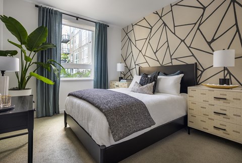 Model bedroom with a large window at Sixth & Jackson apartments in San Jose.