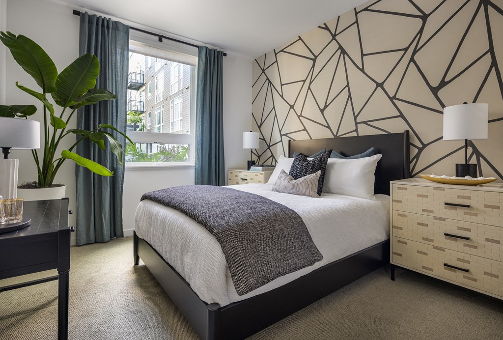 Model bedroom with a large window at Sixth & Jackson apartments in San Jose.