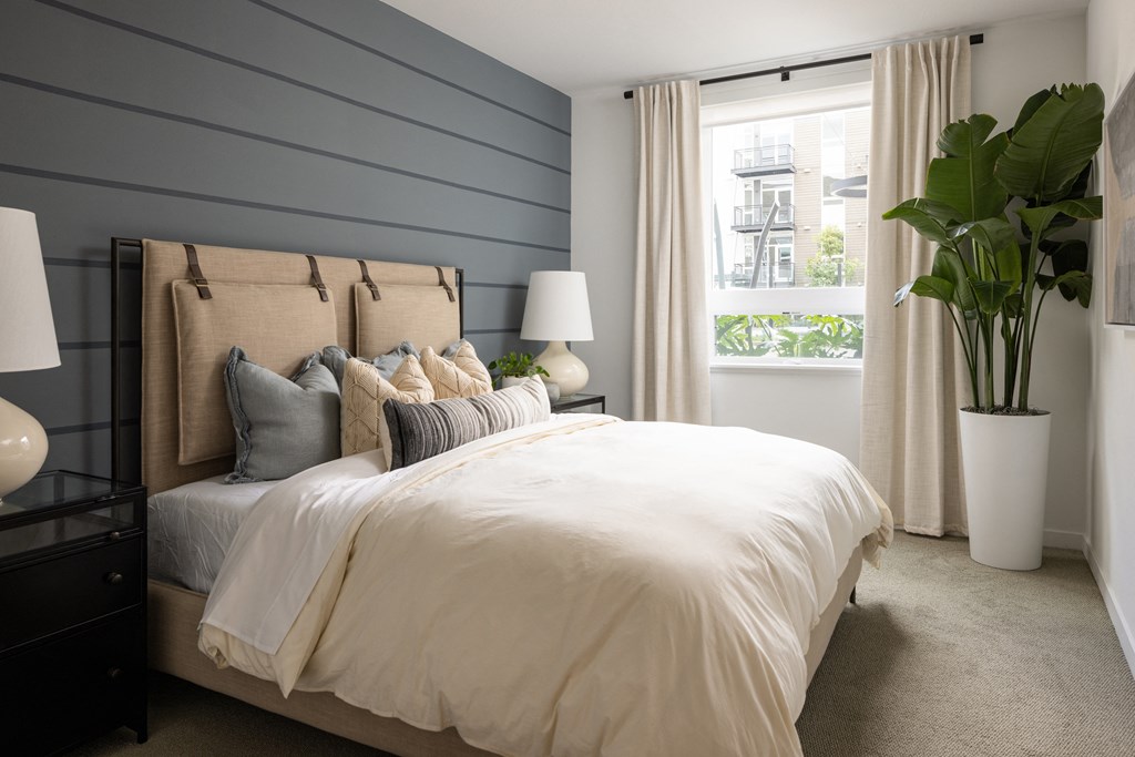 Model bedroom with a large window at Sixth & Jackson apartments in San Jose.