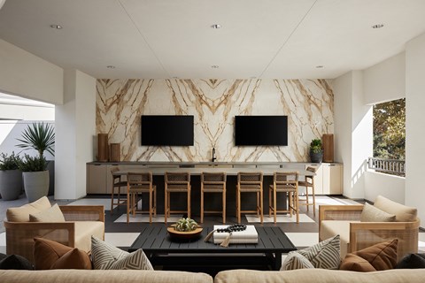 Full kitchen and TV's accompanied by lounge and bar seating at City Lights at Town Center Apartments in Aliso Viejo