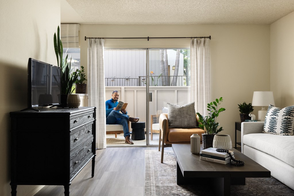 Man reading book in patio space at Cerritos Apartments