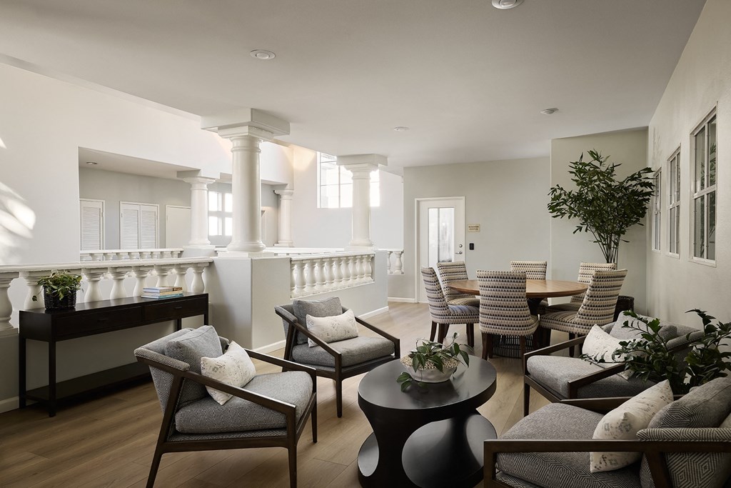 A living room with a white balcony and a grey couch at Valentia Apartments in La Jolla.
