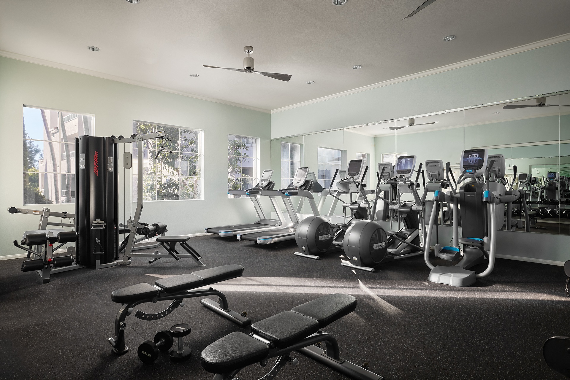 A gym with a variety of equipment including treadmills, weights, and exercise balls at Valentia Apartments in La Jolla.