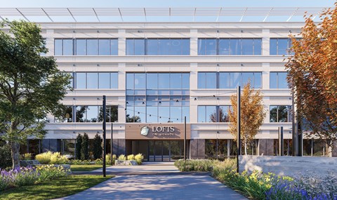 The front office building with large windows and greenery lining the pathway at Lofts on Monaco in Denver.