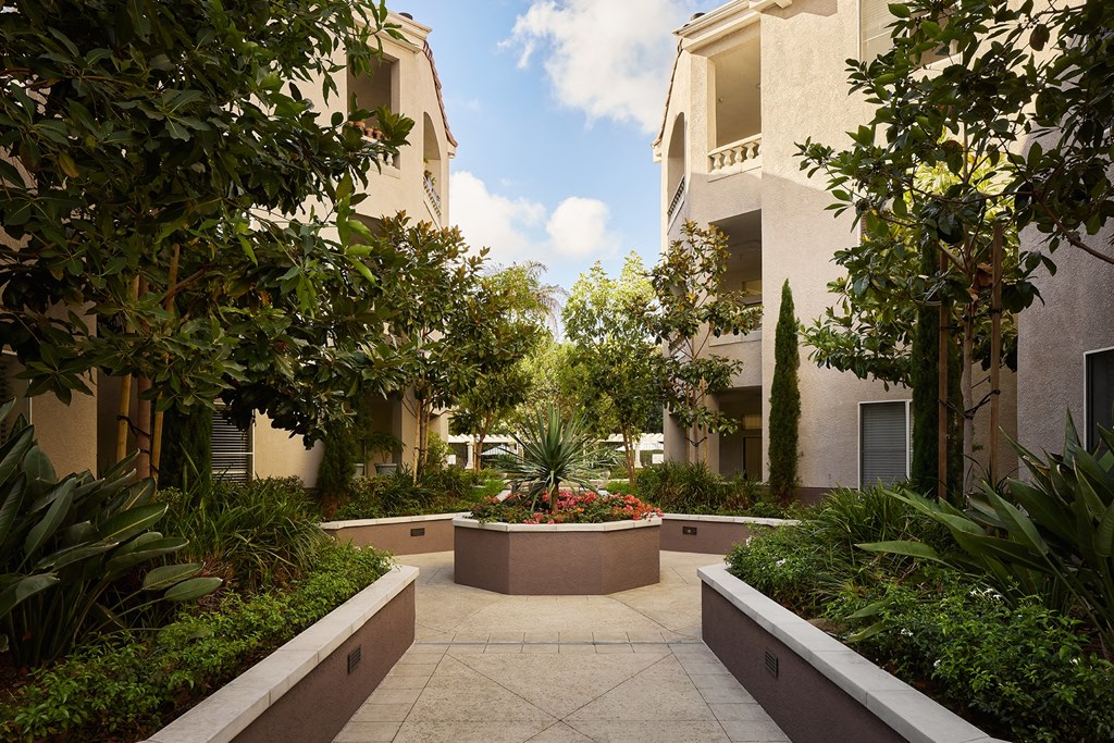 A courtyard with a fountain surrounded by buildings and trees at Valentia Apartments in La Jolla.