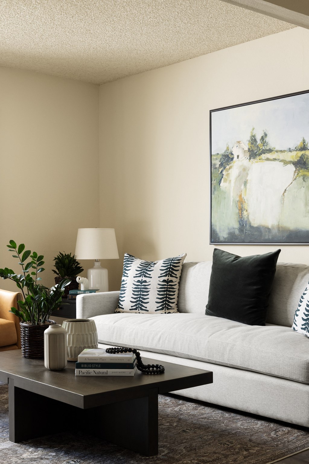 Living area with couch and pastoral art at Cerritos Apartments