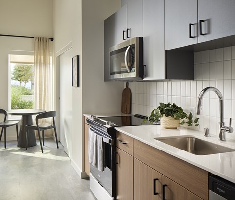 A modern kitchen with a sink, oven, and a window with curtains.