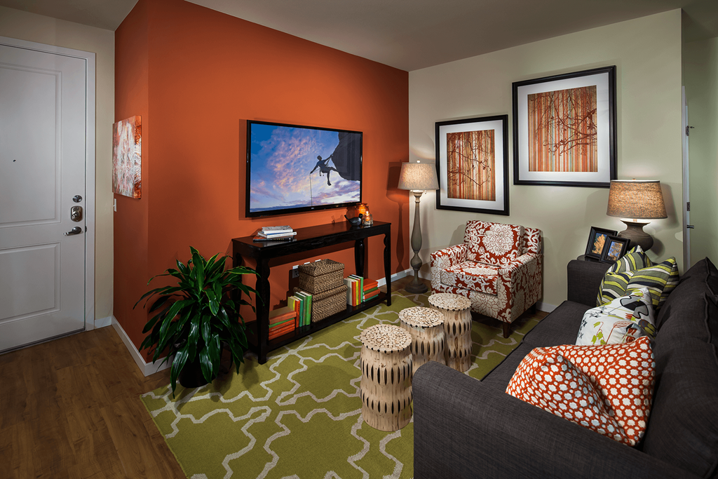 Model living room with an orange accent wall at Zenith Meridian apartments in Englewood.