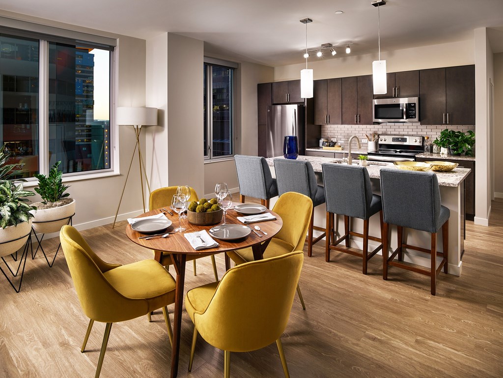 A modern dining room with a round table and yellow chairs.