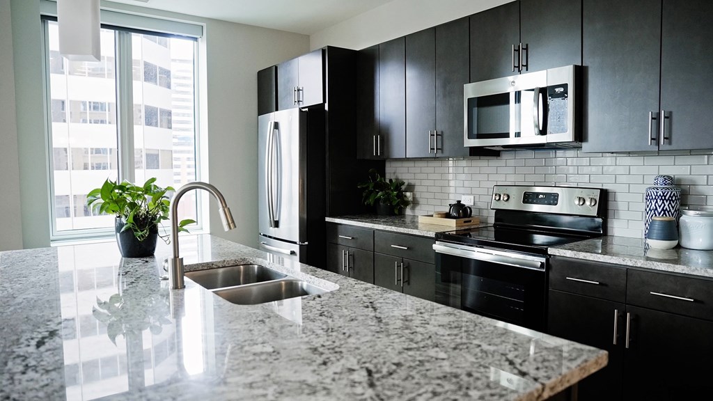 A kitchen with black cabinets and a granite countertop.