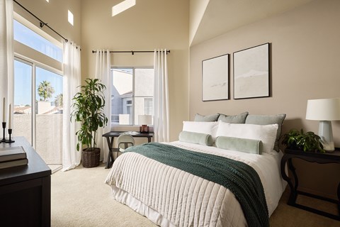A bedroom with a large bed and a desk with a chair.