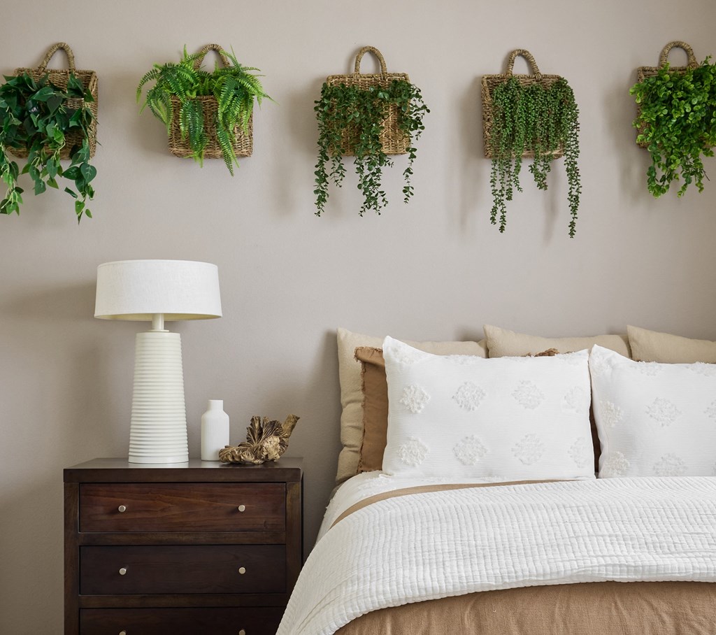 A bedroom with a bed, nightstand, and wall-mounted planters at Valentia Apartments in La Jolla.