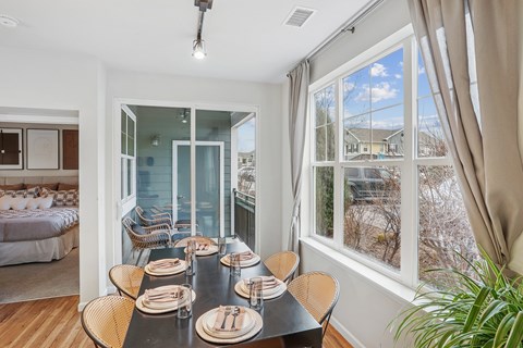 A dining room with a table set for six with a view of the backyard.