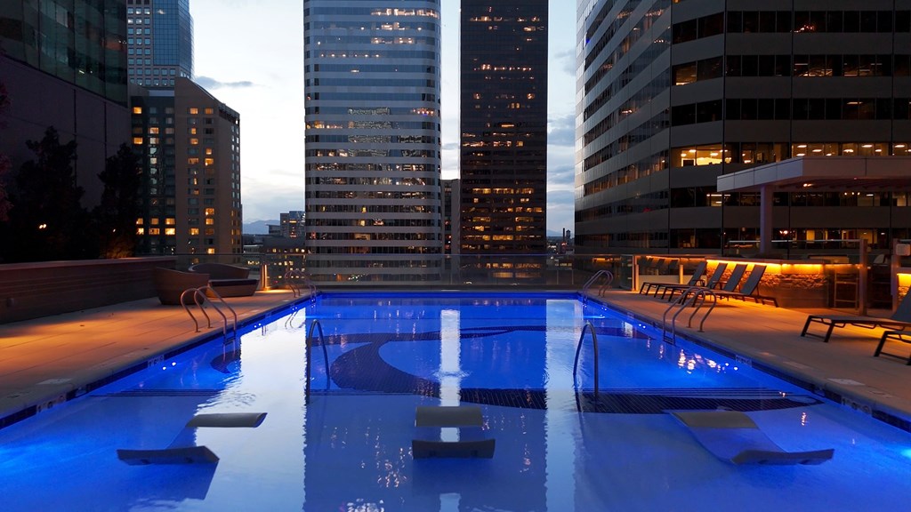 A swimming pool with a cityscape at dusk.