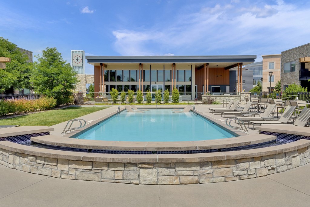 Pool with in-pool loungers and spa at Vela Meridian Apartments in Parker