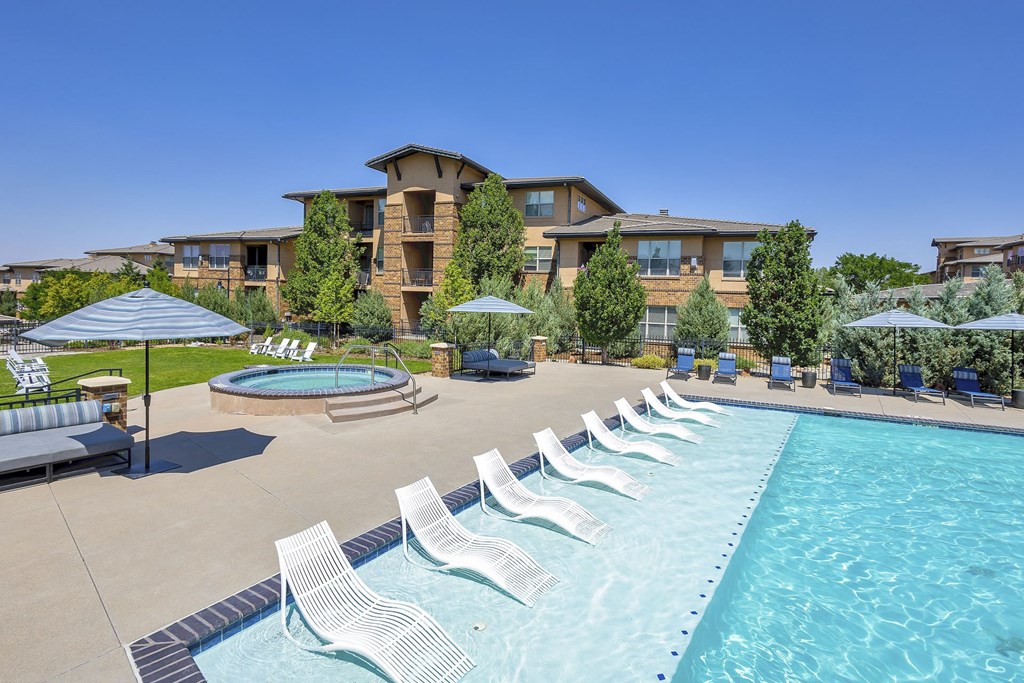 Resort-style pool with chaise lounge chairs and umbrellas at Zenith Meridian apartments in Englewood.