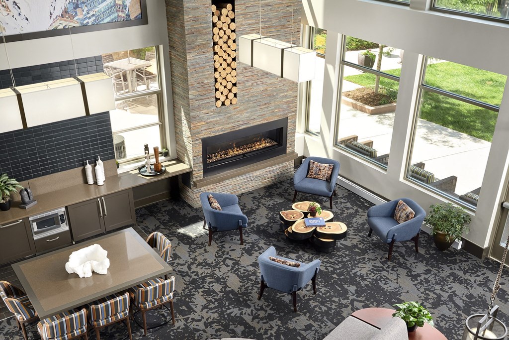 Resident lounge with carpet and blue chairs for seating at Zenith Meridian apartments in Englewood.