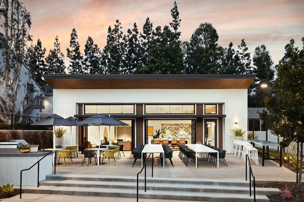 Outdoor patio with tables and chairs and a building with large windows at Seaside at Laguna Heights apartments in Laguna Niguel.
