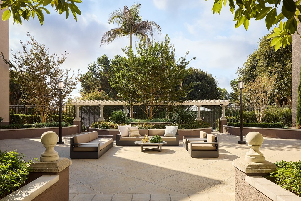 A patio with a table and chairs surrounded by trees at Valentia Apartments in La Jolla.