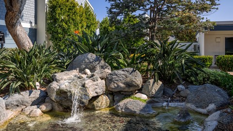 Outdoor rocks with a small waterfall at Crystal Springs apartments in Fountain Valley.