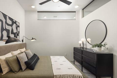 View of a bedroom in the model with a ceiling fan at Lofts on Monaco Apartments in Denver.