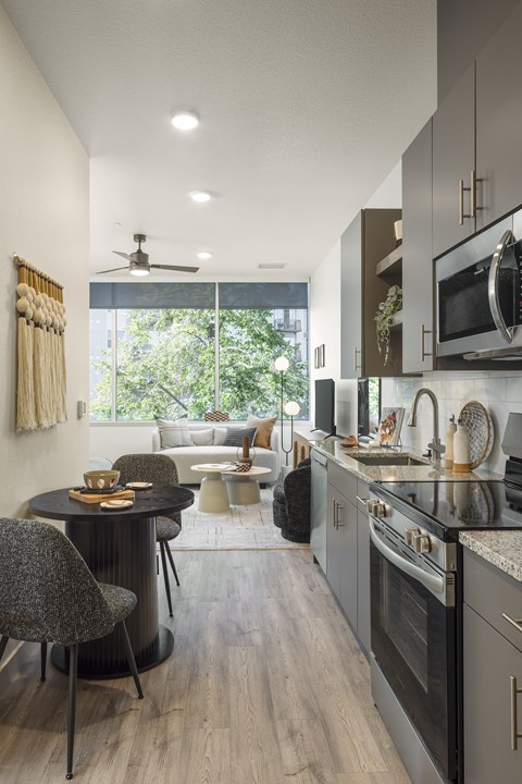 View of the kitchen with granite countertop and wood-style flooring at Lofts on Monaco Apartments in Denver.