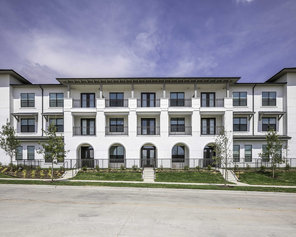 a large white building with a blue sky in the background lots of windows and arched entryways