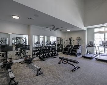 a gym with weights and cardio equipment in a building with windows