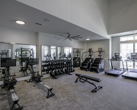 a gym with weights and cardio equipment in a building with windows