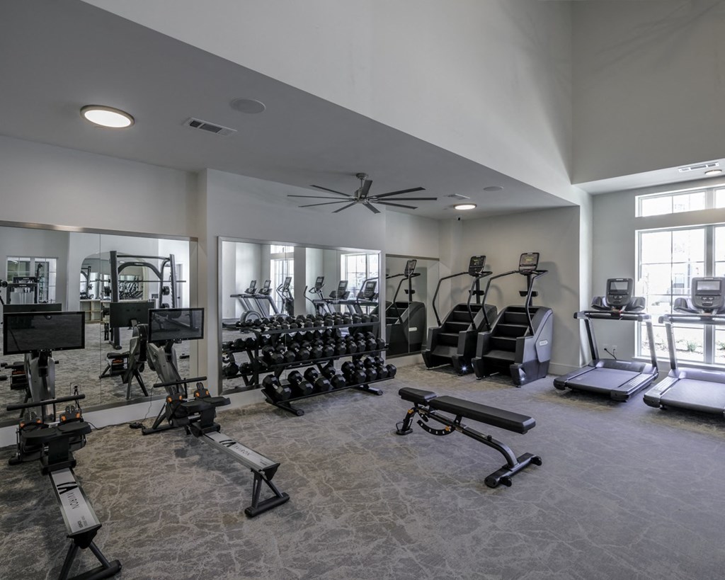 a gym with weights and cardio equipment in a building with windows