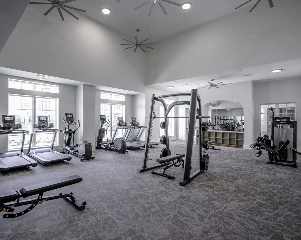 a gym with cardio equipment and weights in a building with windows