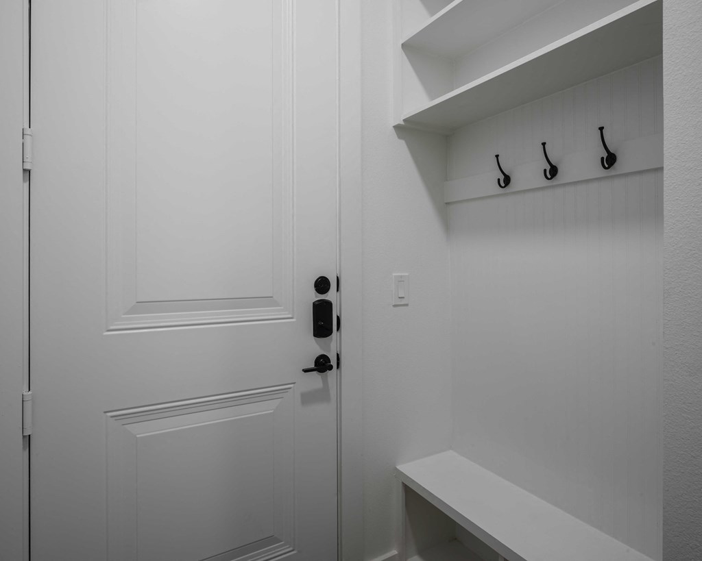 a white door with a black door knob and black hooks on the wall entryway
