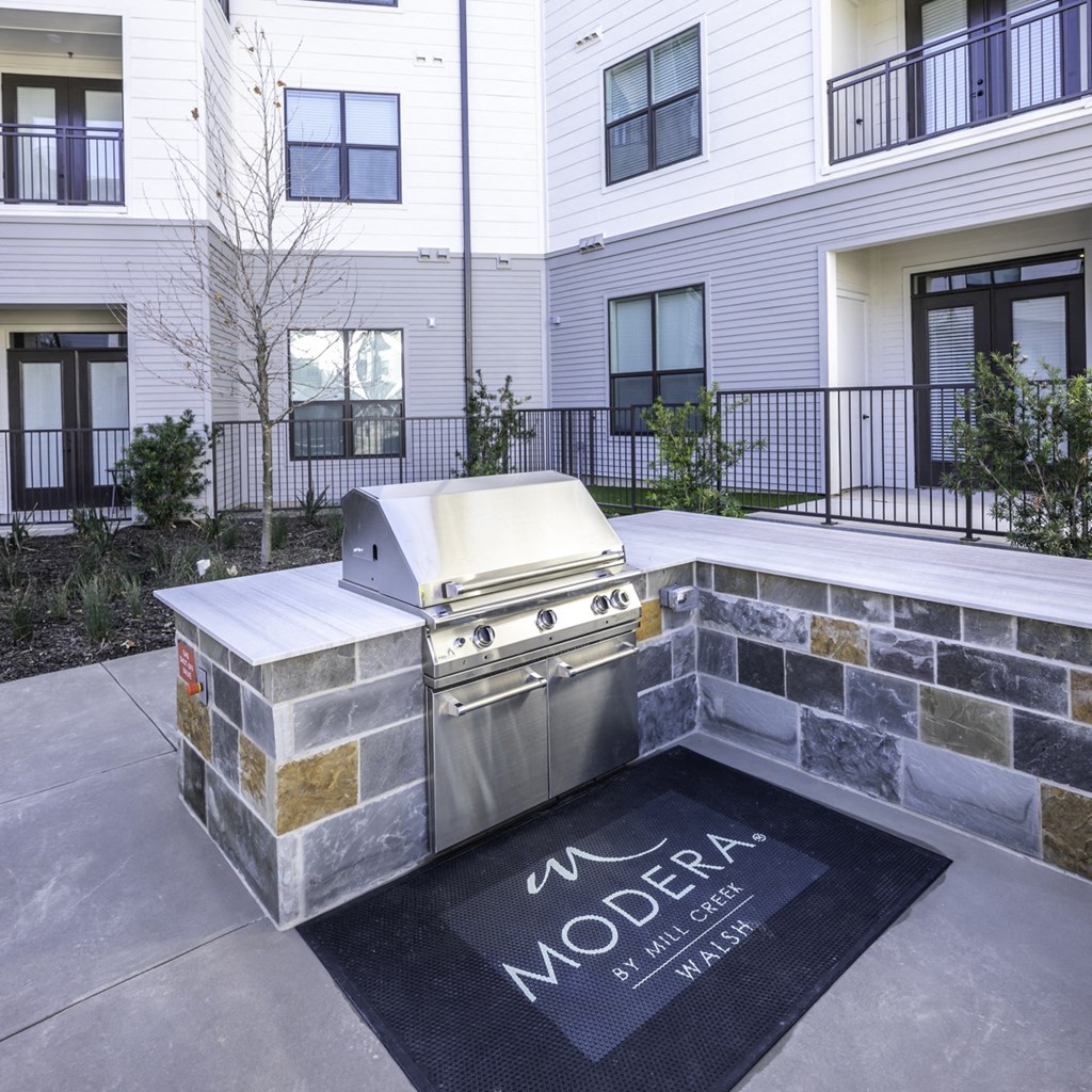 an outdoor kitchen with a grill and a rug in front of a building