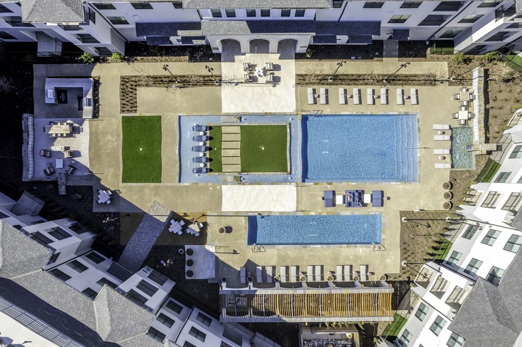 an aerial view of a building with a pool and grass
