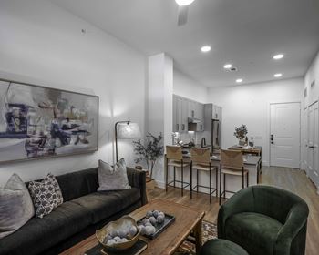 a living room and kitchen with white walls and hardwood floors