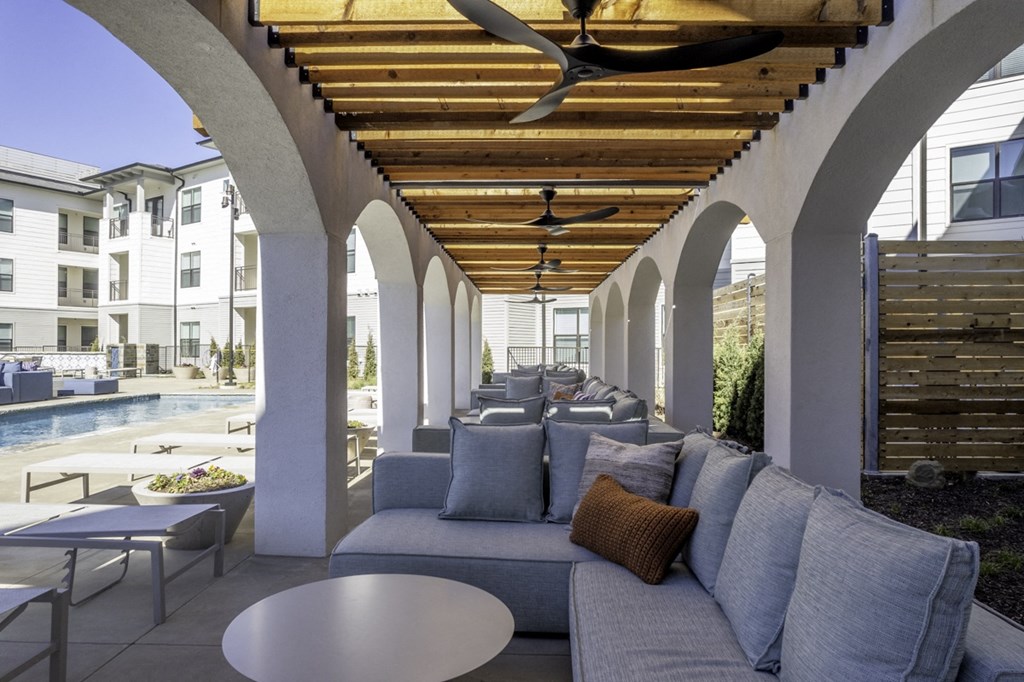 a lounge area with a couch and tables and a swimming pool