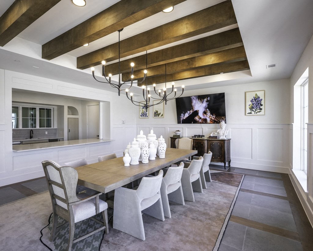 a dining room with a long wooden table and white chairs