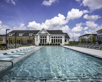 a large pool with lounge chairs and a building in the background