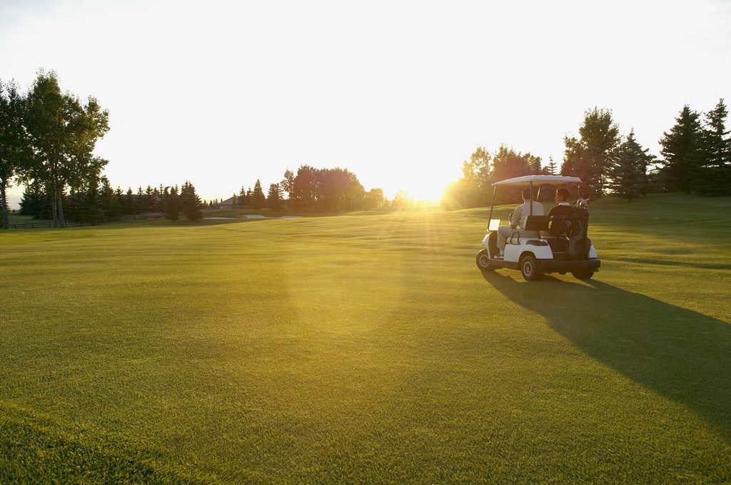 a golf cart parked on a golf course at sunset