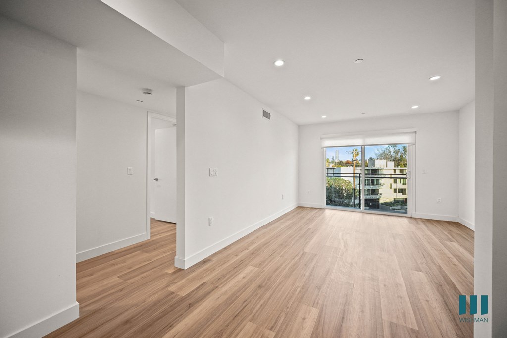 A large empty room with wooden floors and white walls.