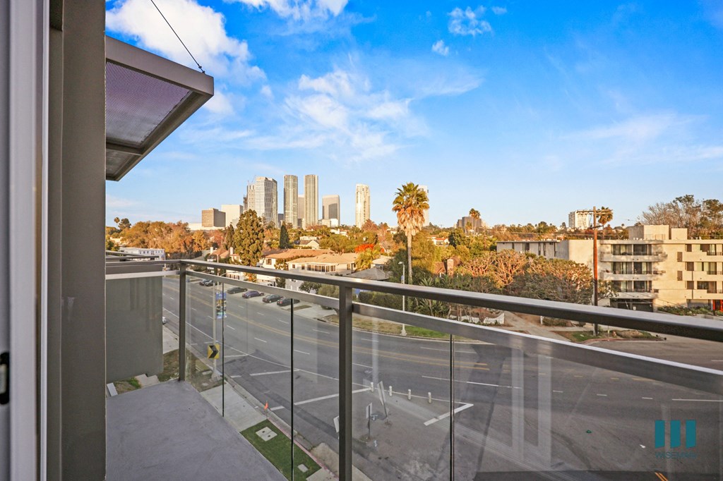 A view from a balcony overlooking a city street with buildings in the distance.
