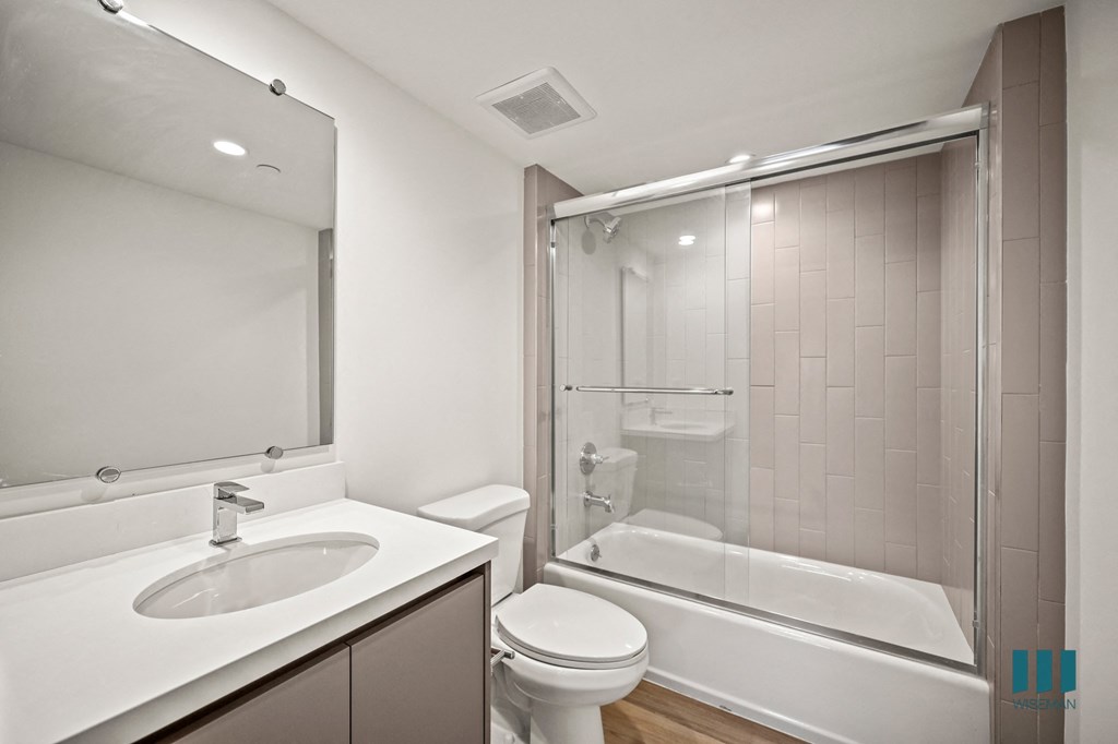 A modern bathroom with a white sink, toilet, and bathtub.