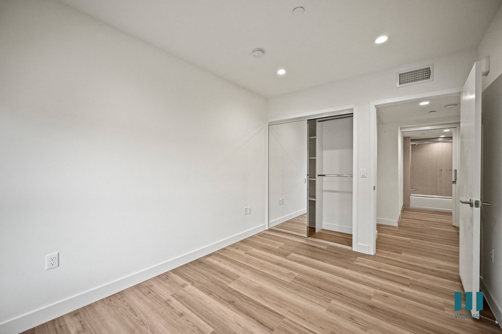 A long hallway with wood floors and white walls.