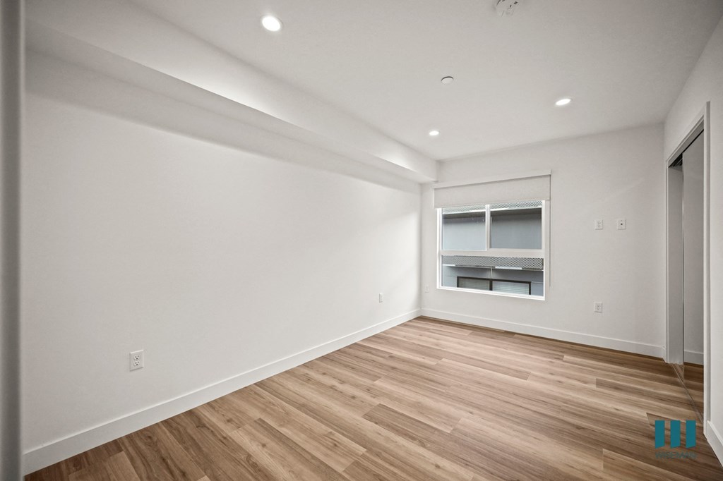 A spacious room with wooden flooring and a window.