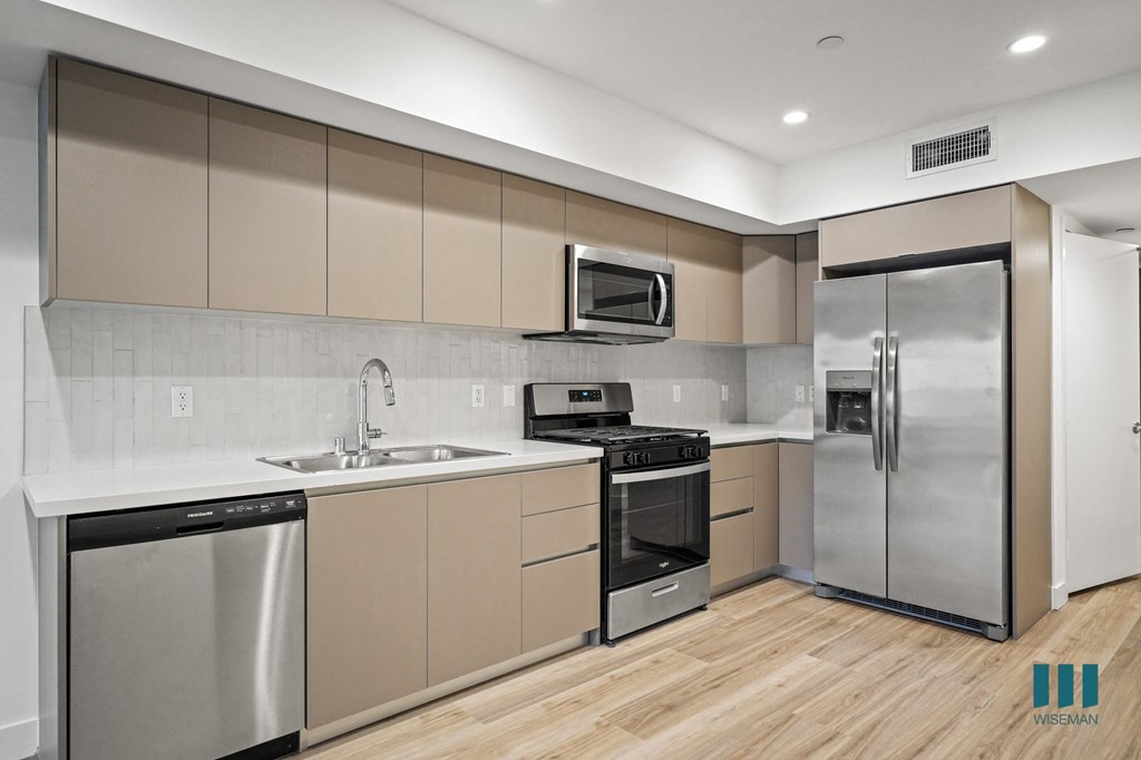 A modern kitchen with stainless steel appliances and wooden floors.