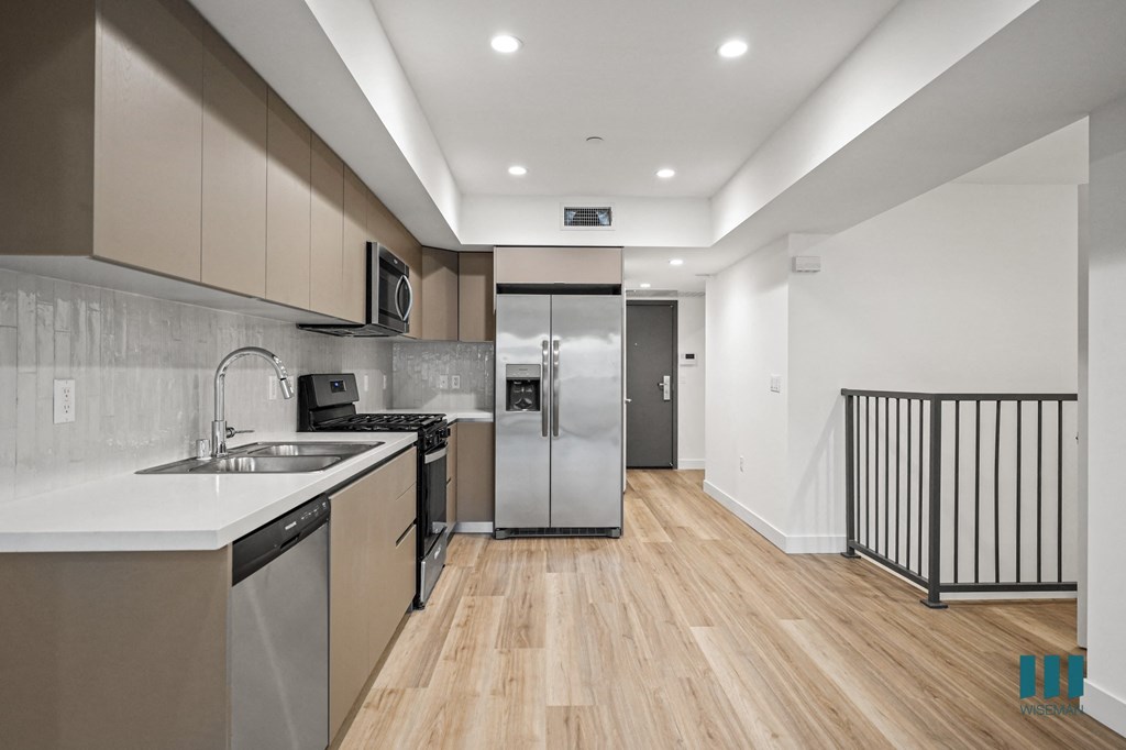 A modern kitchen with wooden floors and stainless steel appliances.