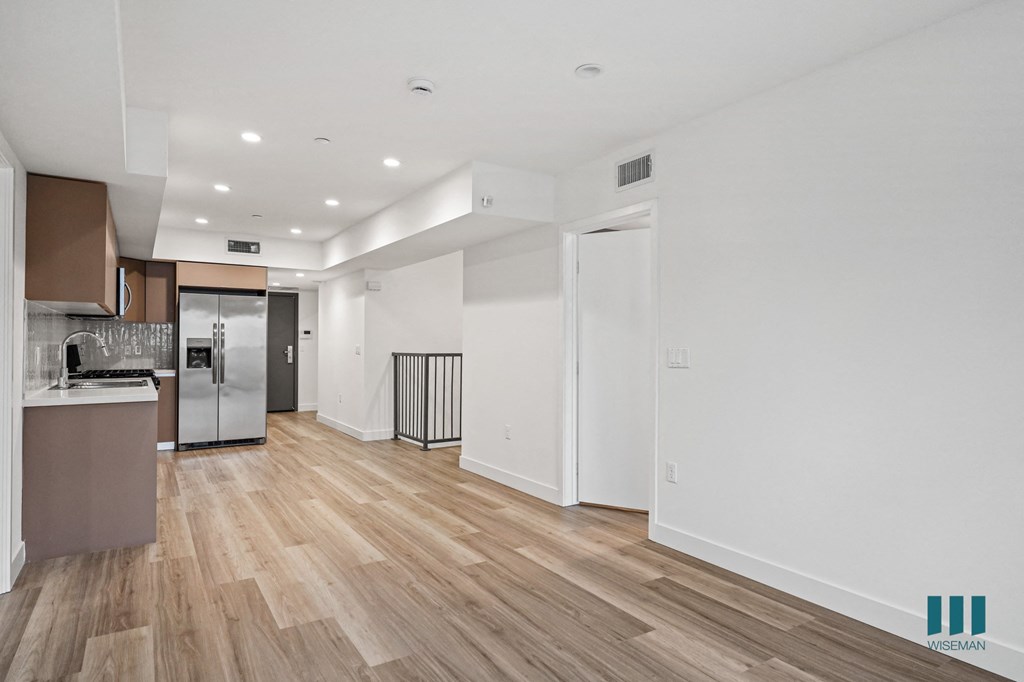 A kitchen area with a refrigerator, sink, and cabinets.